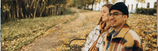 Couple sitting on bench together in fall 