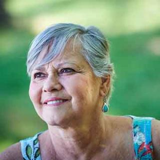 older woman with short gray hair smiling into distance