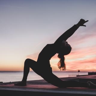 silhouette of a woman doing sunrise yoga 