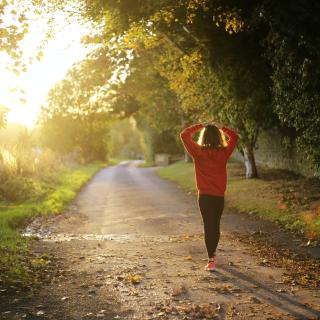 woman walking on path in sunlight