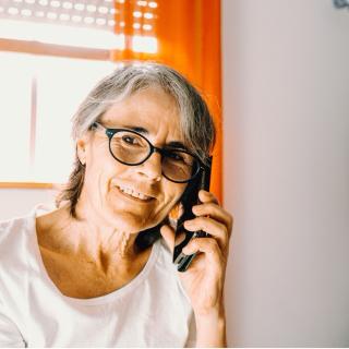 Elderly woman smiles as she talks on the phone