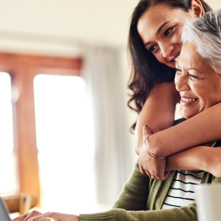 A mother and daughter smiling in front of a laptop