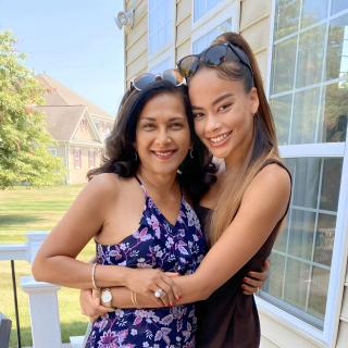 Cassie and her mom smile and embrace side by side outside on a patio