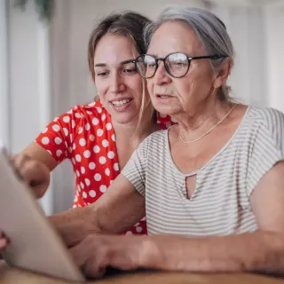 Two seated women review information on a tablet