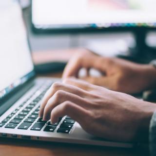 Man's hands typing on laptop keypad
