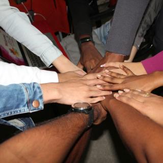 Many people hands meet at the center of their circle