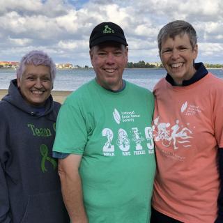 Friends who helped Dianne smile together in front of a lake