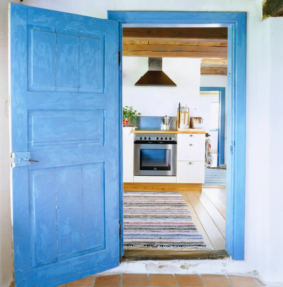 A kitchen beyond a bright blue door