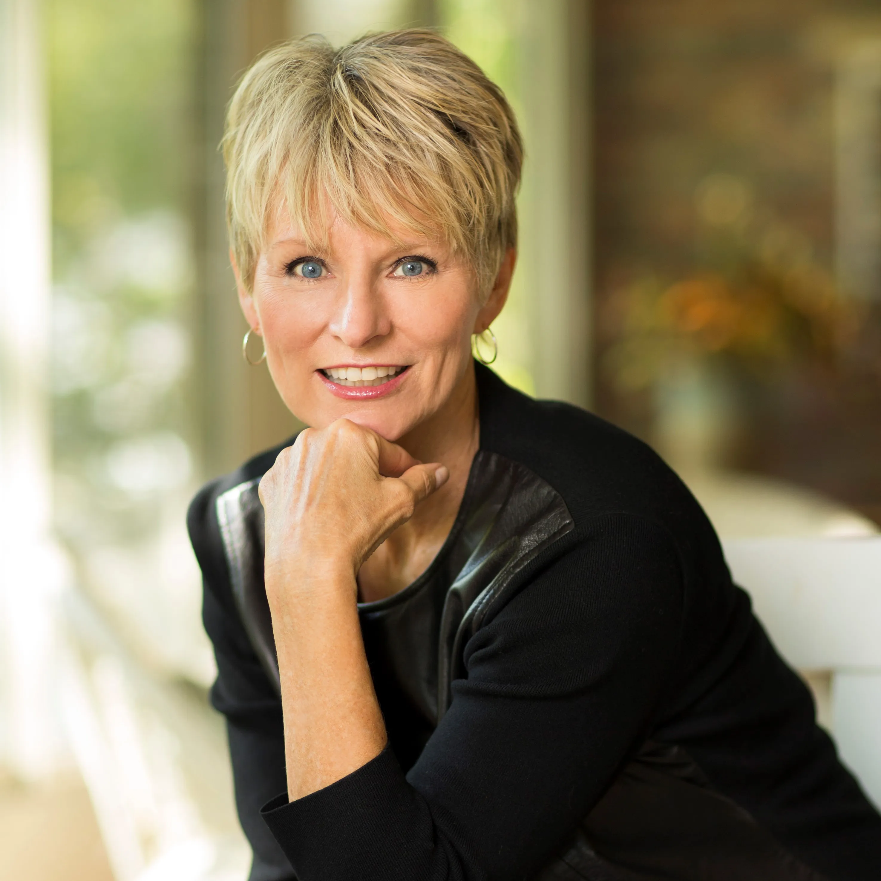 Cancer survivor, author, and survivorship advocate Judy Pearson smiles with her chin resting on her hand 