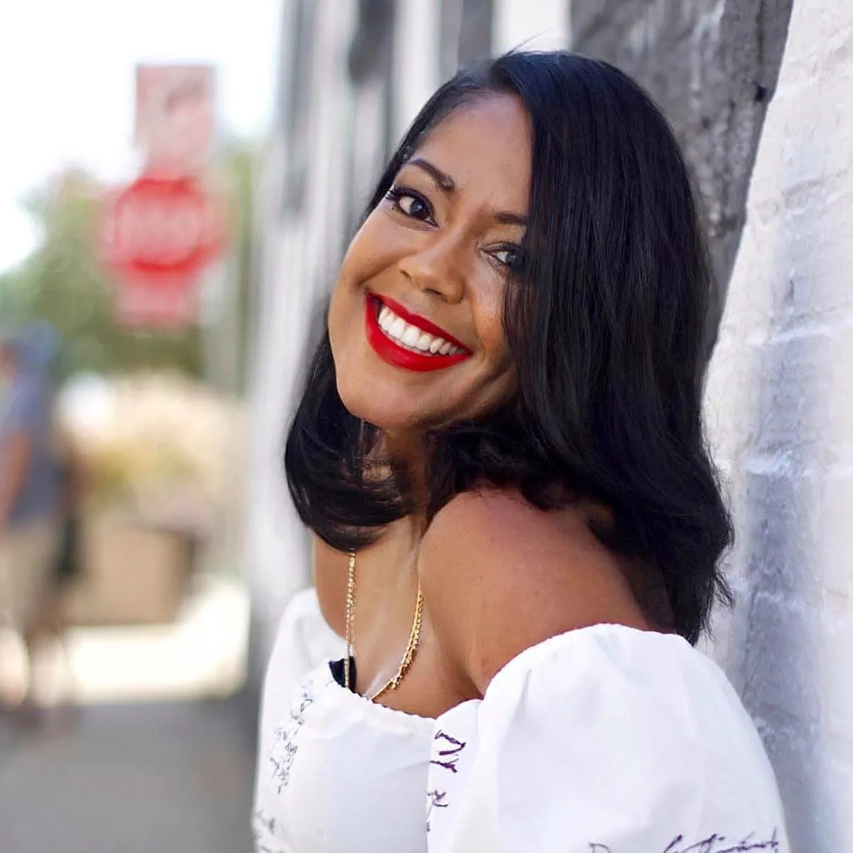 Evelina, a breast cancer survivor, smiles wide on a city sidewalk