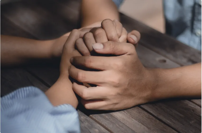 Hands fold over another pair of hands in a comforting manner