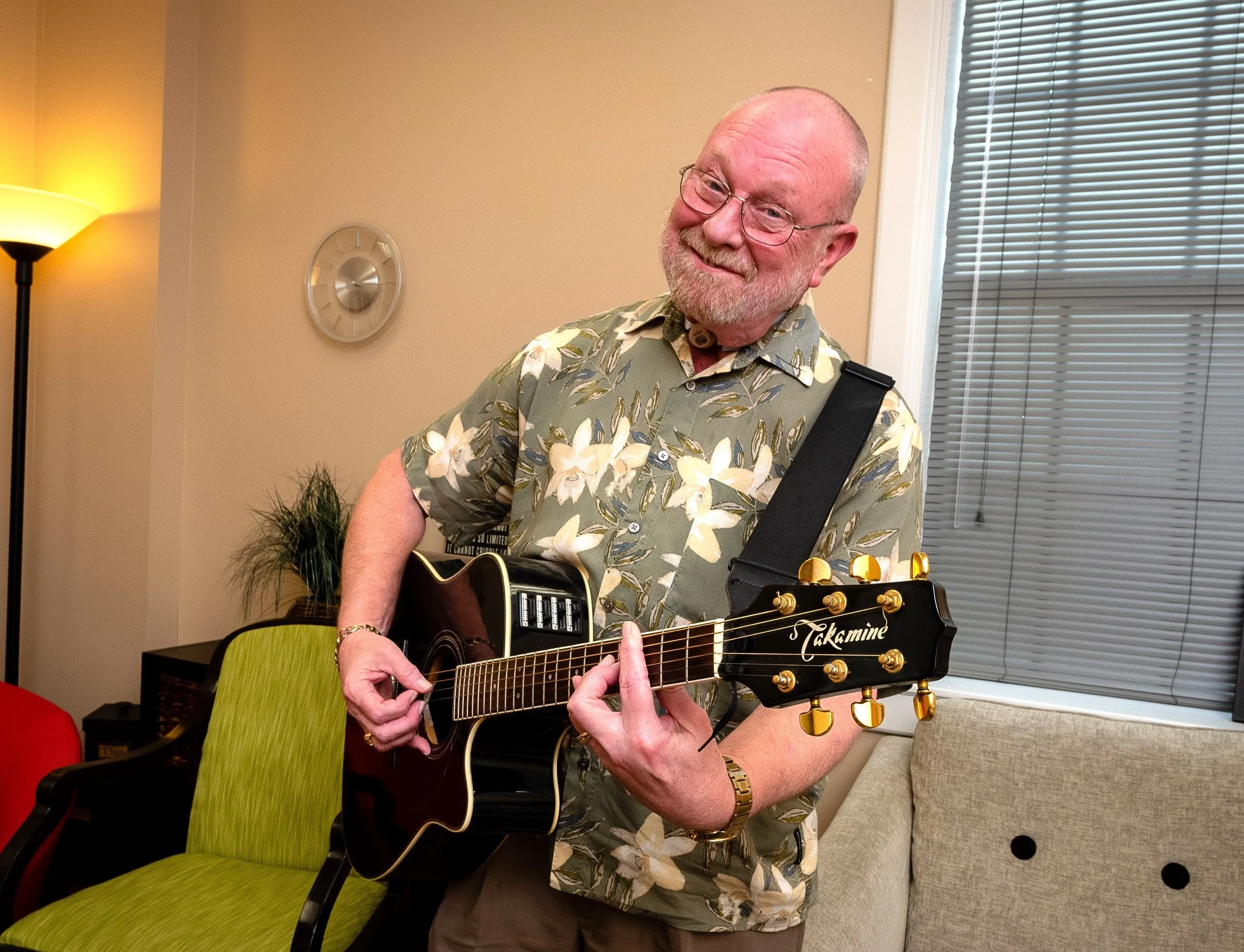 Terry smiles while playing the guitar in a bright-lit room