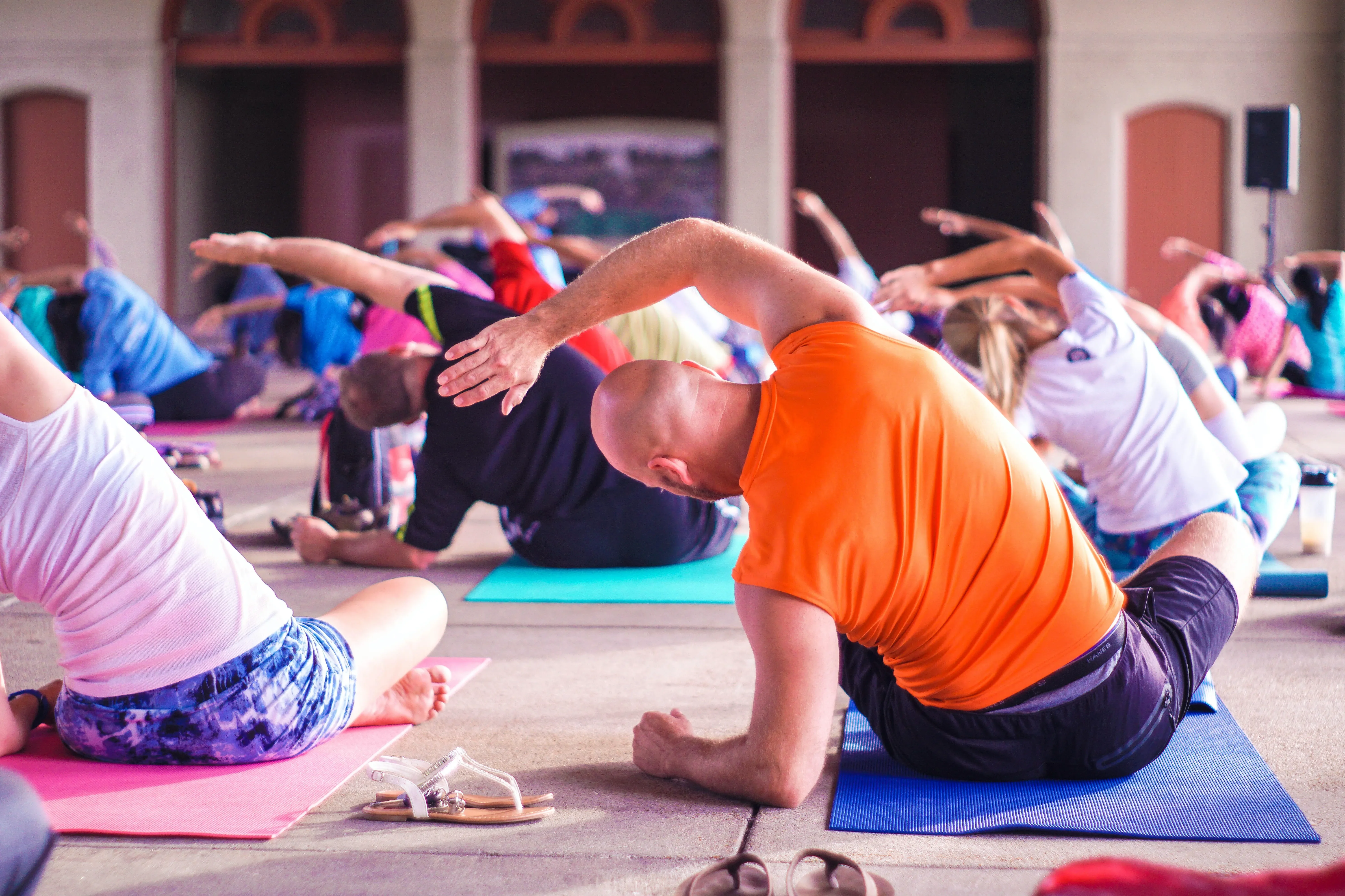 A group of men and women practice yoga on their mats in an exercise studio