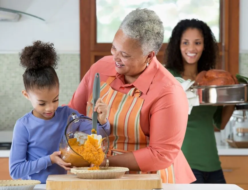 A family cooks a turkey and side dish in their sunlit kitchen