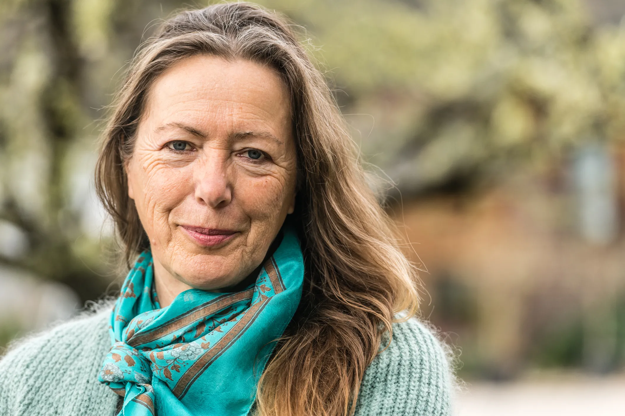 a middle aged woman outdoors wearing a scarf slightly smiling at the camera