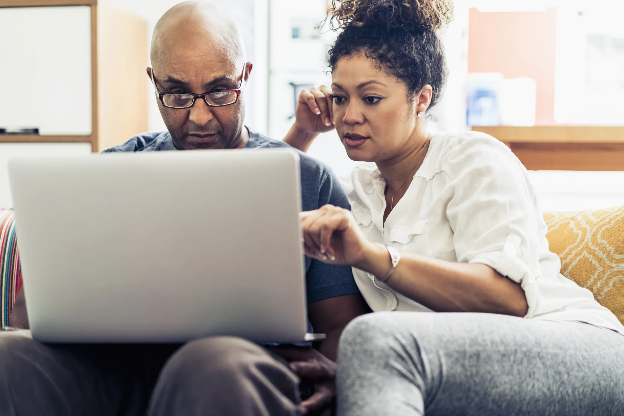 Man and woman looking at a laptop together on the couch