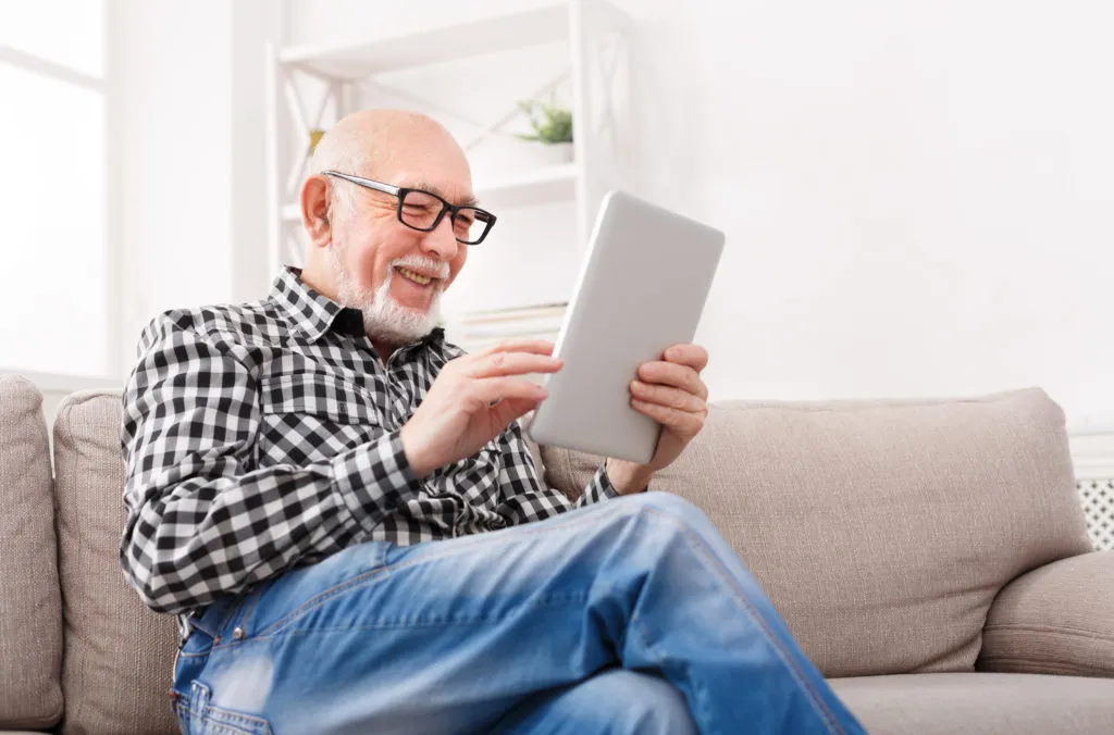 A man smiling while looking at a tablet