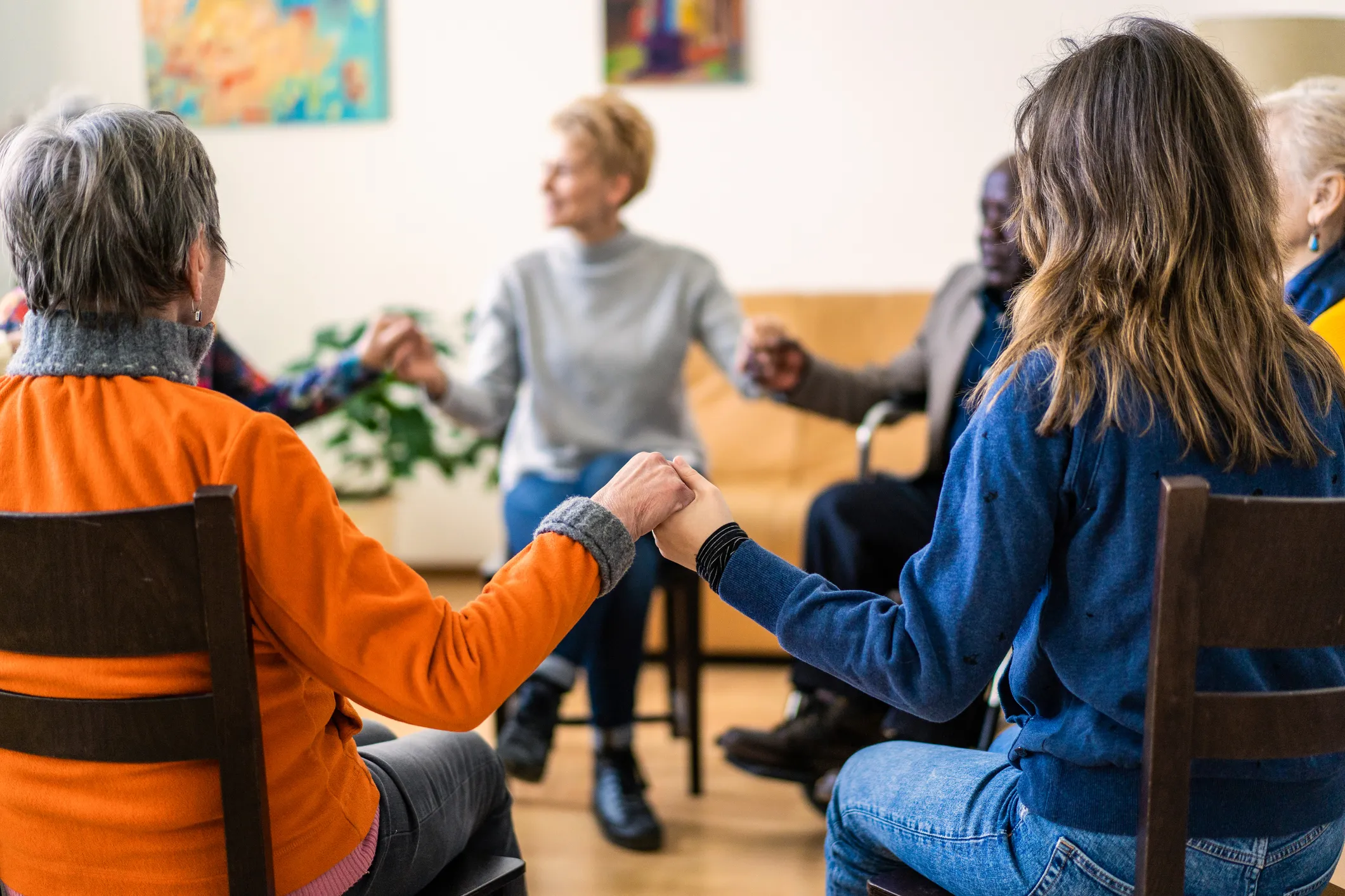A seated group of adults hold hands