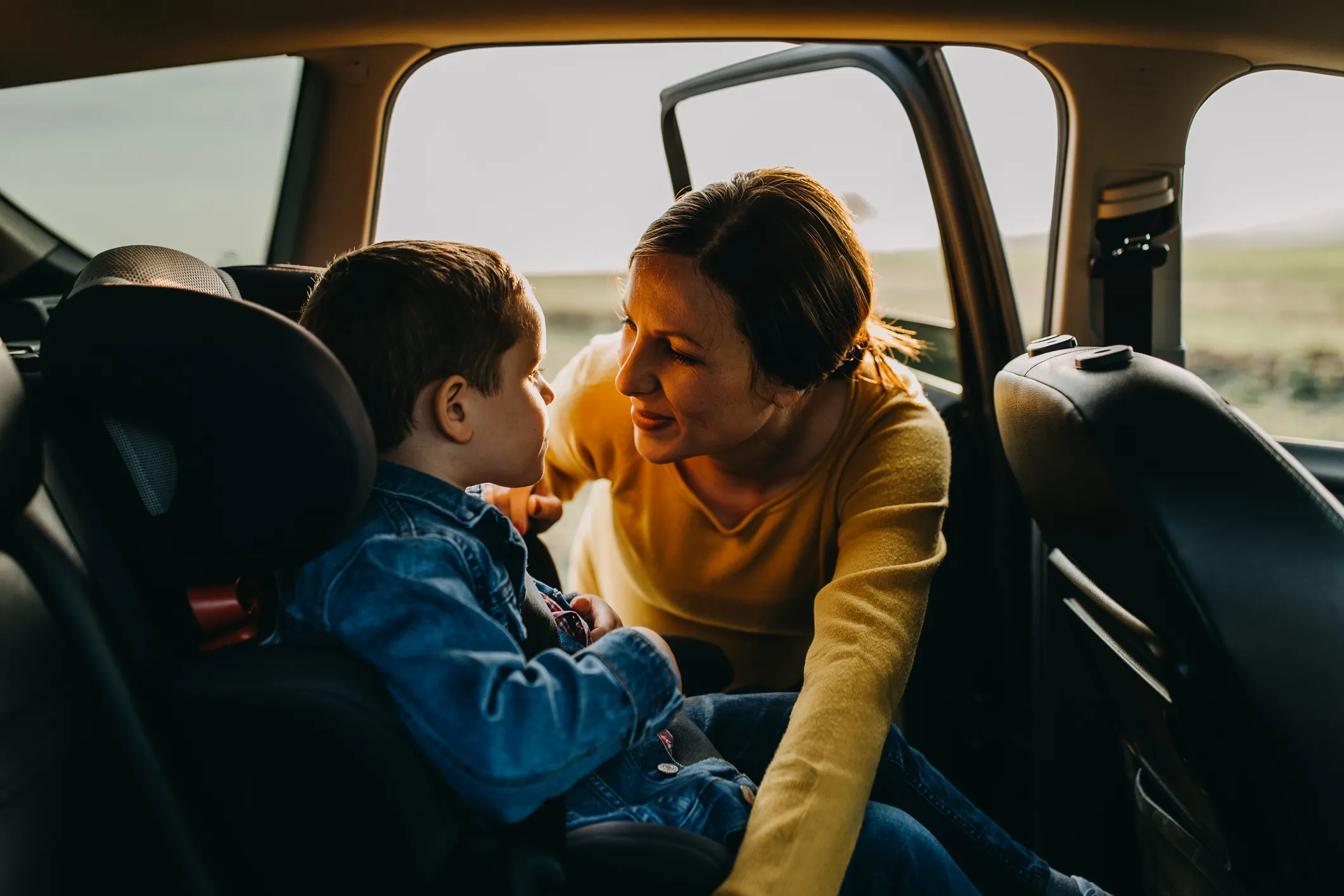Mother helping child into car seat