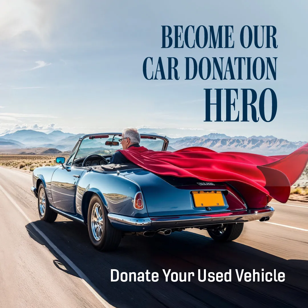 A gentleman driving away in a car with a superman cape