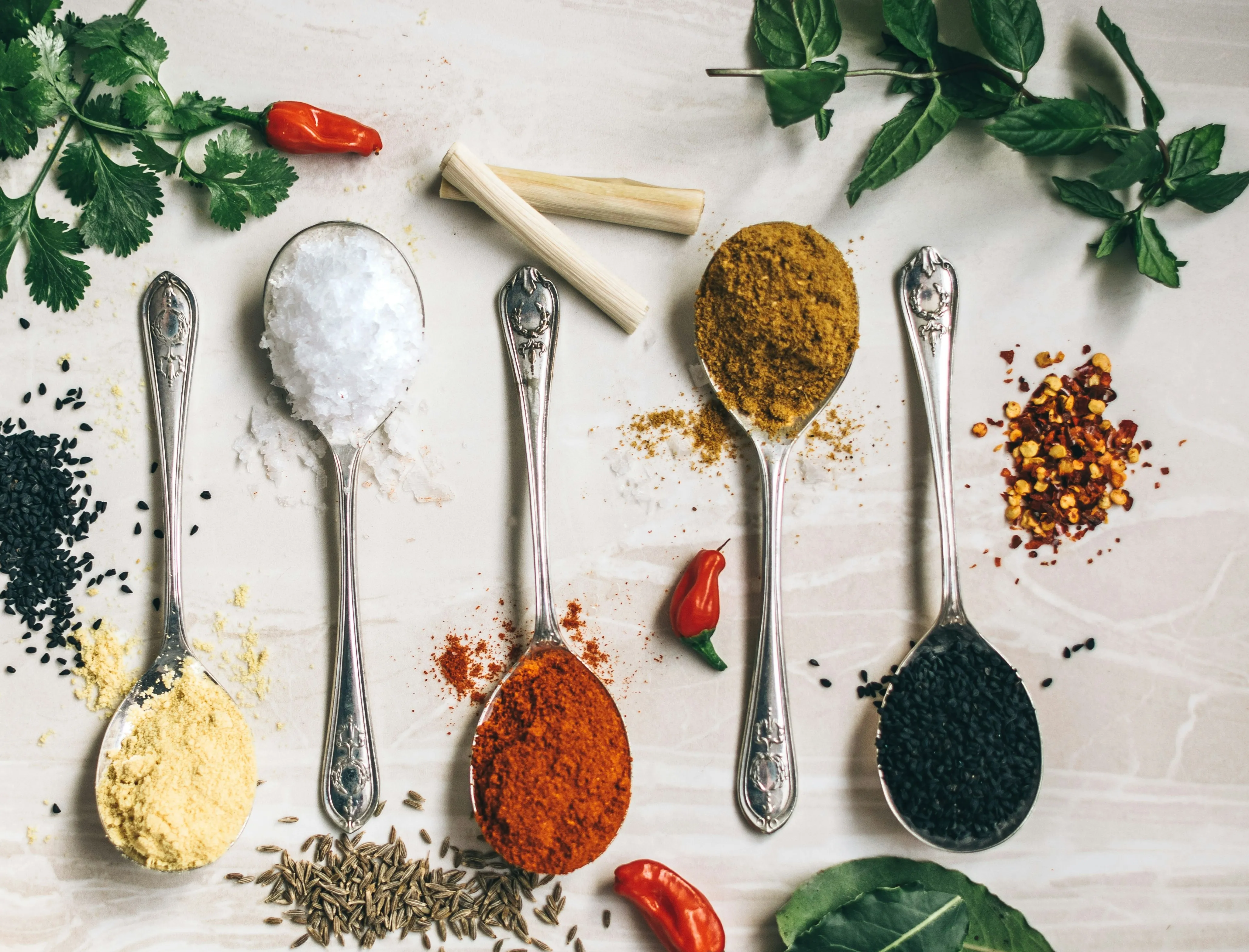 Five spoons filled with colorful spices on a table