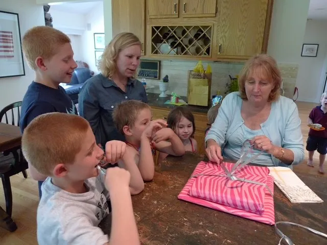 Sally and her children watch as her mother-in-law opens a gift.