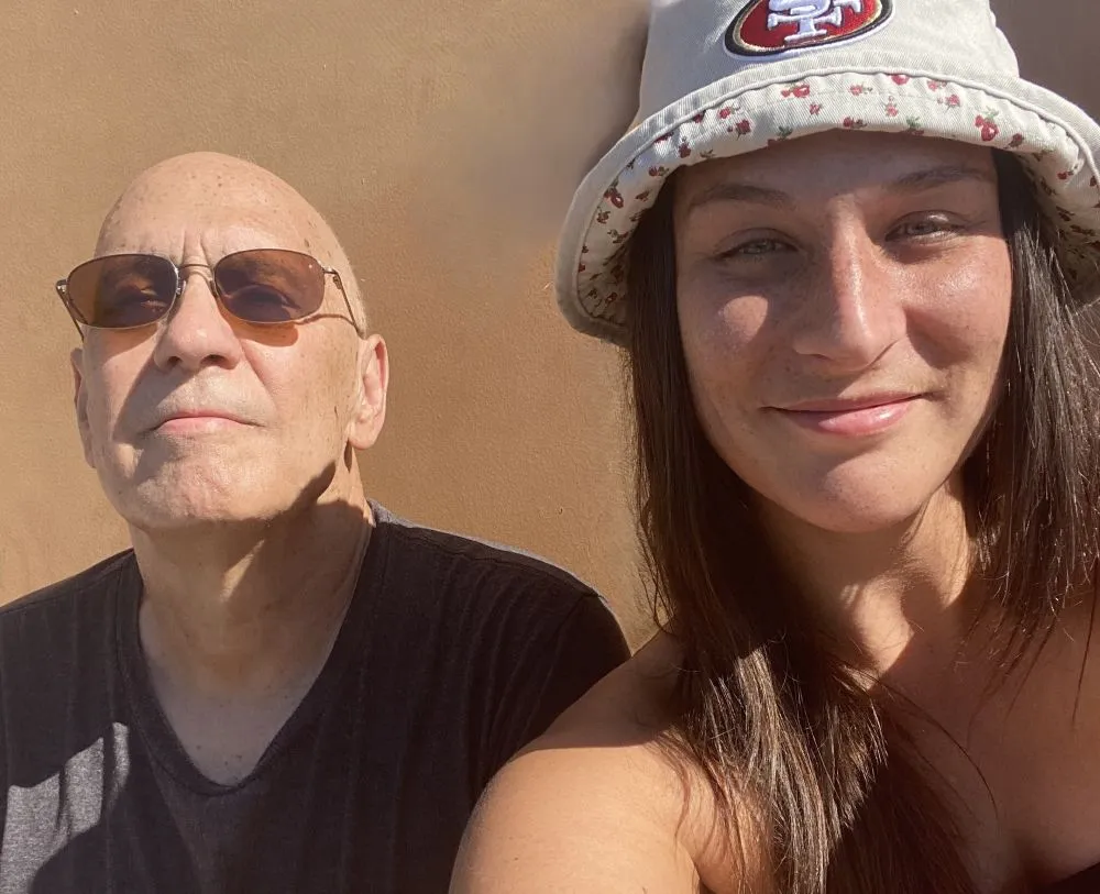 Jeffrey smiles with his daughter in a sunny location