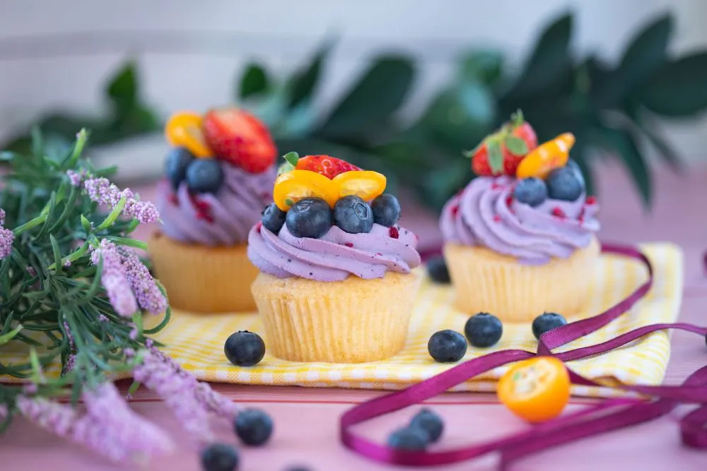 Cupcakes with purple icing and color fresh fruit toppings