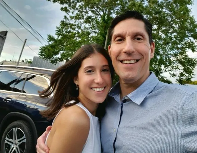 Kayla and her dad smile for an outdoor photograph together