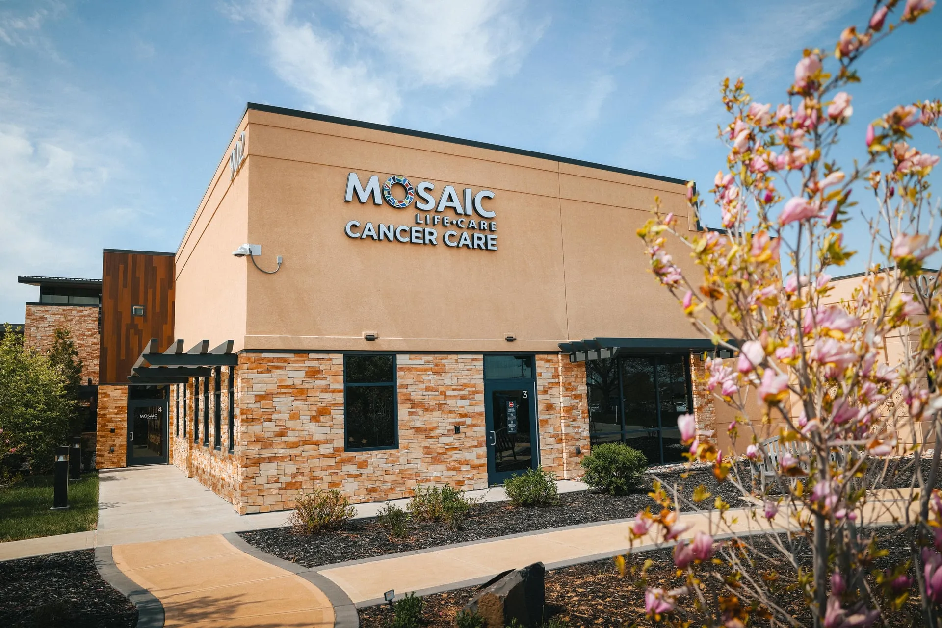 Front view of Mosaic Life Care cancer center with pink flowering tree