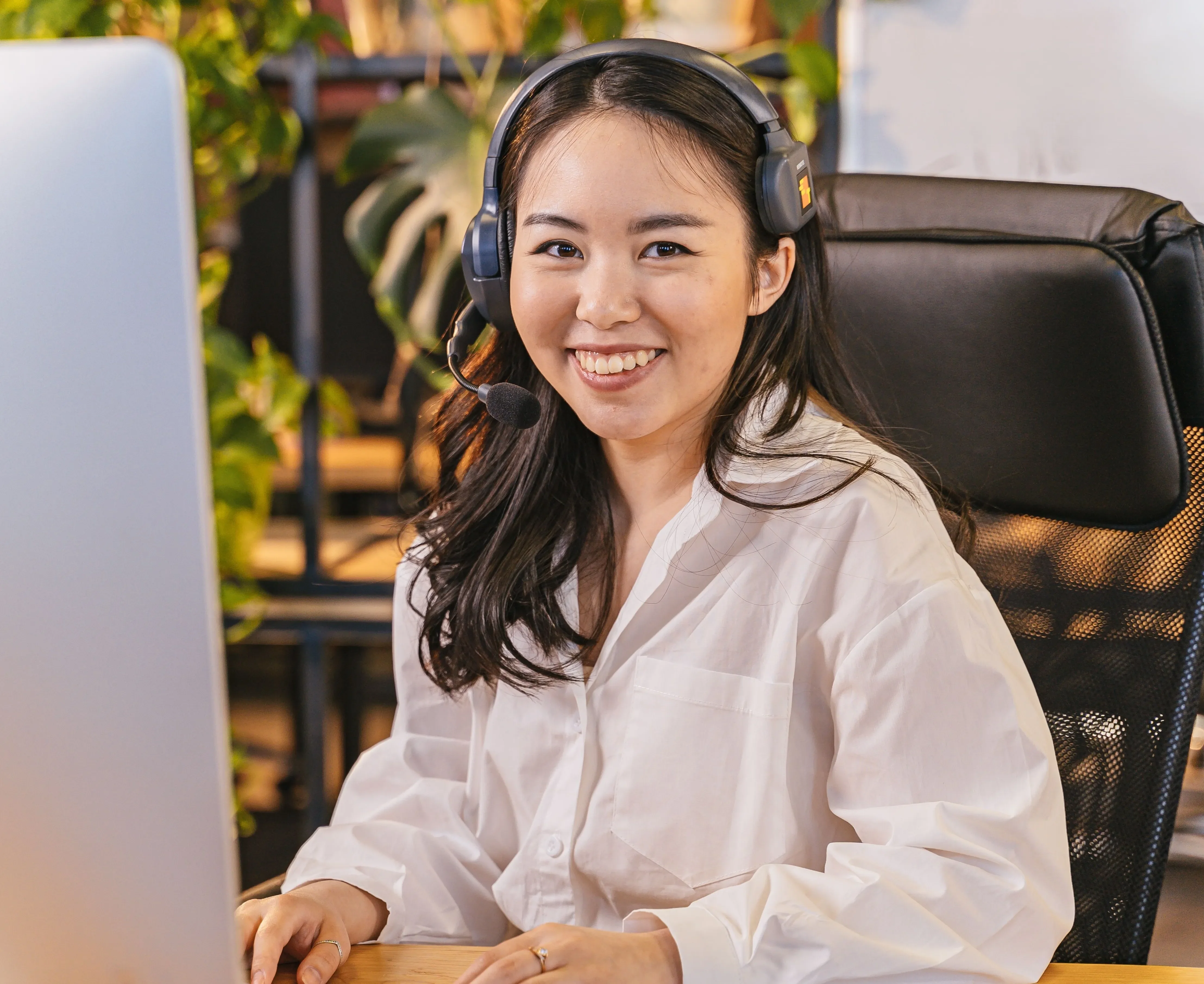 A friendly smiling phone operator sits at an organized desk