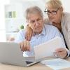 older white couple looking at a laptop and papers