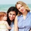 two women and a baby smiling and embracing on the beach