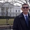 white man wearing a coat and tie in front of white house