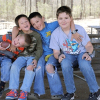 four young boys on a picnic table embracing and smiling