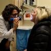 female doctor shining a flashlight into a female patient's mouth