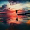 person standing strong on a beach with a sunrise view