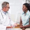 A doctor talks with a patient about her health care decisions in a medical office.