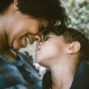 A smiling mother snuggles with her young son