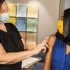 A medical worker wearing a mask examines the arm of a patient who is also wearing a mask
