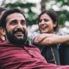 A man lies in the grass at a park and smiles with friends