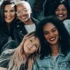 A diverse group of smiling women sit together on a stairwell