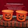 Two trick-or-treating candy buckets with jack-o'-lanterns rest on a doorstep