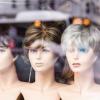 A store window features women mannequin heads with different wig styles