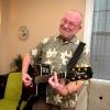 Terry smiles while playing the guitar in a bright-lit room