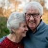 An elderly couple laughs and snuggles together outside