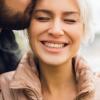 Lady smiling while being kissing on the forehead