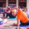A group of men and women practice yoga on their mats in an exercise studio