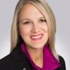 A headshot of CSC's new CEO Debbie Weir shows her smiling and wearing a purple blouse and black blazer with a cancer awareness ribbon lapel pin