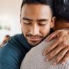 A young man smiles and looks peaceful while hugging his friend